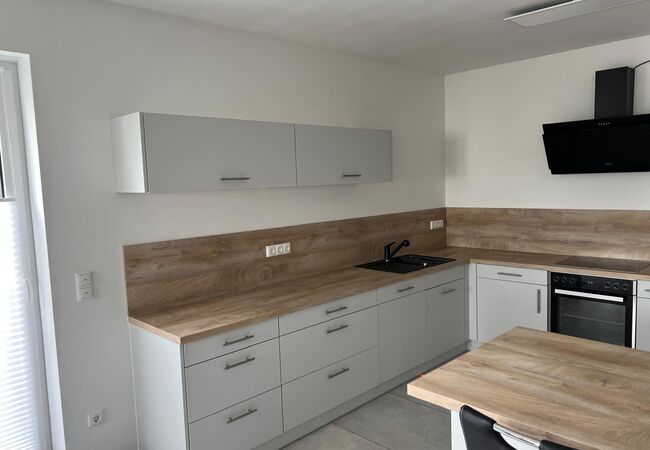 Ansicht des fertigen und aufgebauten Küchenschranks mit Arbeitsplatte, Spüle, Herd und Schubladen sowie Hängeschrank